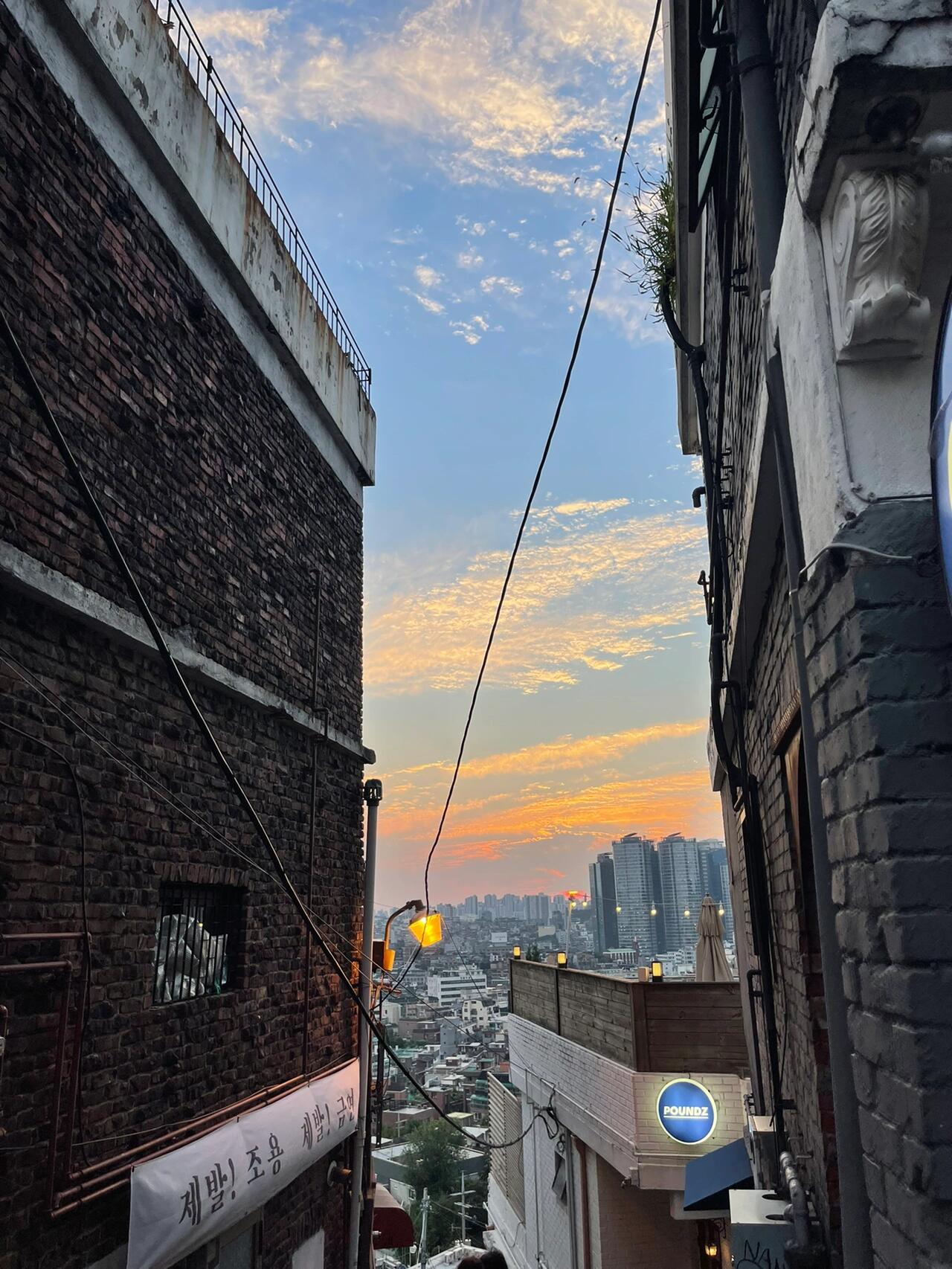 
                        ?? 梨泰院日落|走進韓劇的畫面漫步在梨泰院的小巷，和朋友意外發現了一個超級適合拍照的地方！?? 天空的顏色美極了，和兩旁的建筑完美融合，感覺自己就像是韓劇里的女主角一樣！??原來我們不知不覺中來到了梨泰院解放村附近，這里的景色真的太美了，讓人心情大好！?? 順便炫一下，我戴的是宋旻浩同款帽子哦，超級喜歡！??#韓國拍照 #韓國ins風 #首爾景點 #韓國生活 #韓劇風 #韓系風格 #韓系畫報 #韓系時尚 #韓風搭配 #韓風拍照 #日落美景 #氛圍感滿滿 #梨泰院日落 #街頭攝影 #韓國街拍